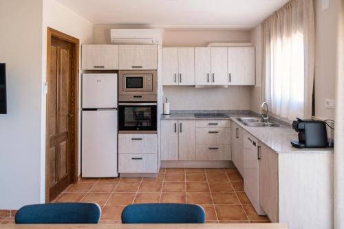 a kitchen with white cabinets and a white refrigerator at Ca l'Apotecari in Calaceite