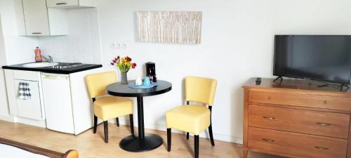 a kitchen with a small table and two yellow chairs at Villa Rose de Mons - Résidence Services Senior in La Brede