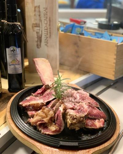a plate of meat on a table with a bottle of wine at Camping Solcio in Lesa