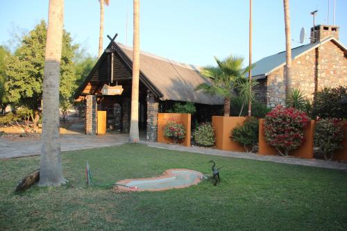 un bâtiment avec une statue sur l'herbe devant lui dans l'établissement Rooisand Desert Ranch, à Chausib