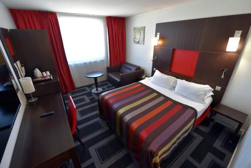 a hotel room with a bed and a chair at Holiday Inn Dijon Toison D'or by IHG in Dijon
