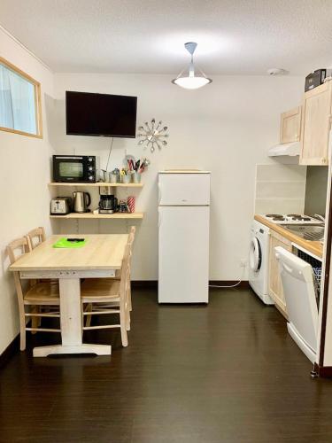 Il comprend une petite cuisine avec une table et un réfrigérateur blanc. dans l'établissement MS APPART** 5 PERS BALCON PISCINE LUZ 5MN, à Luz-Saint-Sauveur