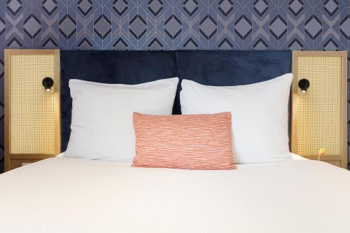 a bed with white pillows and a blue wall at Boutique Apartments Amsterdam in Amsterdam