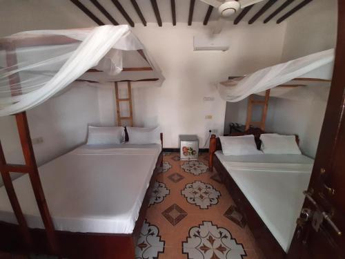 a room with two bunk beds and a tub at AMESbungalows in Nungwi