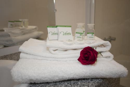 a pile of towels and a rose on a bathroom counter at Hotel Victoria Plaza in Tarija
