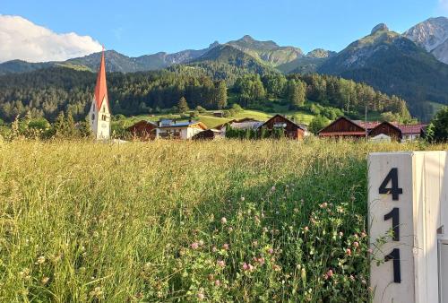 a field of grass with a church in the mountains at Apart Sopherl in Pettneu am Arlberg