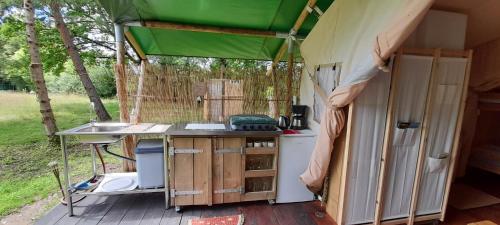 a caravan with a kitchen with a green roof at La lodge du Refuge in Valigny