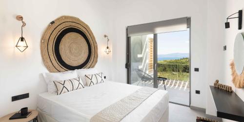 ein Schlafzimmer mit einem großen weißen Bett und einem Balkon in der Unterkunft Koni Villas Agia Paraskevi by Halkidiki Villas in Agia Paraskevi