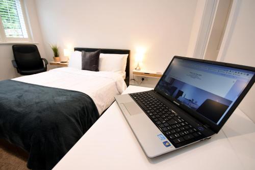 a laptop computer sitting on a desk next to a bed at Apple Tree Place B&B in Tadley
