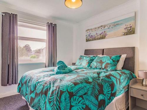 a bedroom with a bed with a green comforter and a window at Lovely Apartment 3 King-size beds in Torquay