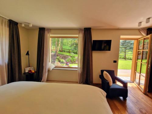 una camera da letto con un letto, una finestra e una sedia di Chalet La Ciaseta a Pozza di Fassa