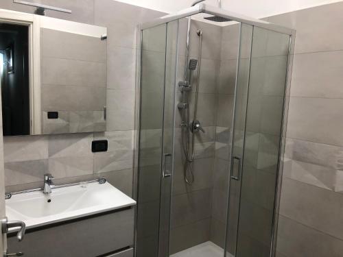 una ducha con una puerta de cristal junto a un lavabo en Panta Rhei, en Villa San Giovanni