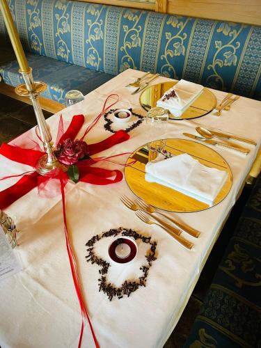 a table with a white table cloth with gold plates and red bows at Hotel Mirabello - Slow Hotel Benessere in Fiera di Primiero