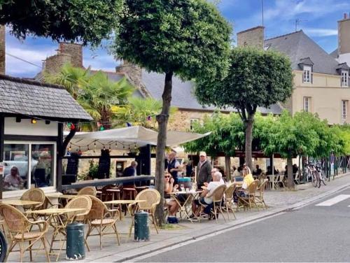 a group of people sitting at tables on a city street at Appartement Cosy 1 chambre pour 2 pers - rénové - terrasse - parking in Dinard