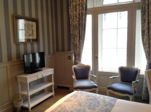 a room with two chairs and a television and a bed at Hotel Patritius in Bruges