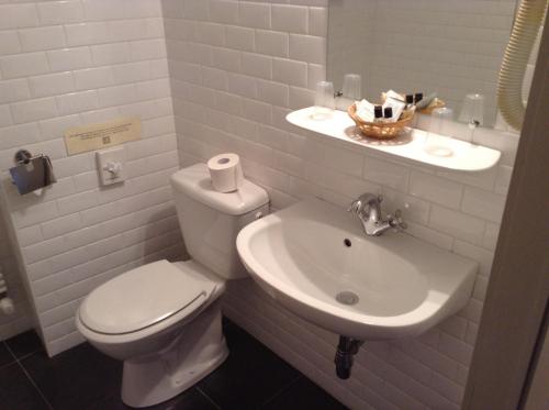 a white bathroom with a toilet and a sink at Hotel Patritius in Bruges
