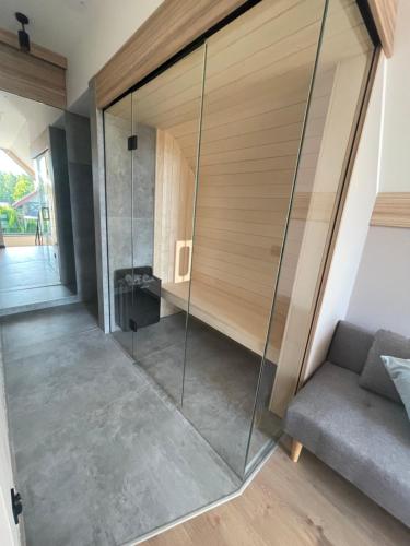 a glass shower in a room with a couch at Marina Nawigator - Domy Wakacyjne in Mikołajki