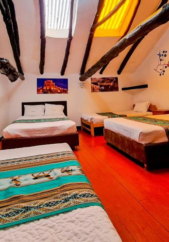 a bedroom with four beds in a room with wooden floors at Ccapaq Wasi in Cusco