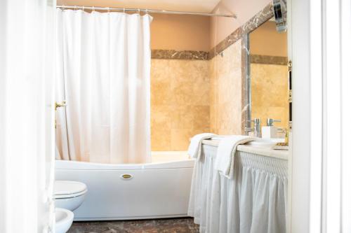 a bathroom with a tub and a toilet and a sink at Hotel Villa Taormina in Taormina