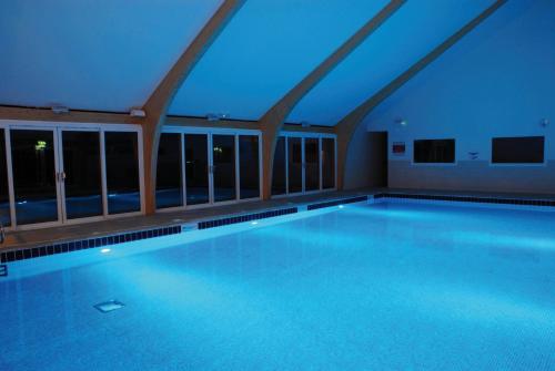 a large swimming pool with blue lighting in a building at Fistral hot tub house for 8 on Retallack Resort in Newquay