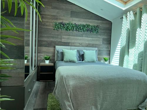 1 dormitorio con 1 cama y pared de madera en Jungle lodge en Lymington