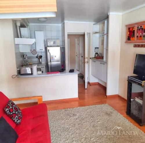 a living room with a red couch and a kitchen at Departamento pie de pista Nevados de Chillán in Pinto