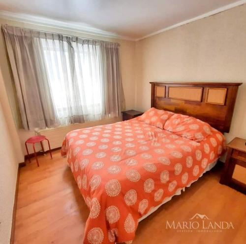 um quarto com uma grande cama laranja e uma janela em Departamento pie de pista Nevados de Chillán em Pinto