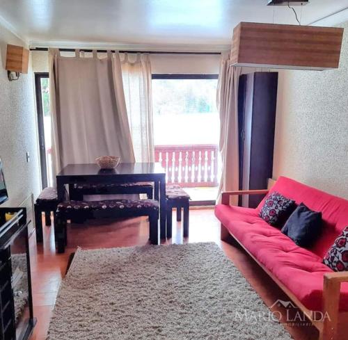 a living room with a red couch and a piano at Departamento pie de pista Nevados de Chillán in Pinto