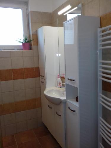 a white bathroom with a sink and a mirror at Balatoni Mandala Vendégház in Balatonszemes