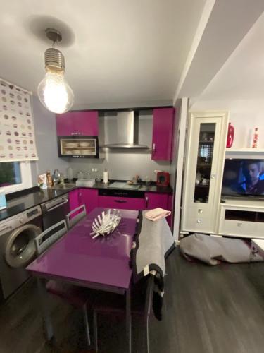 una cocina con armarios morados y una mesa púrpura. en Casa en la playa, en Pobra do Caramiñal
