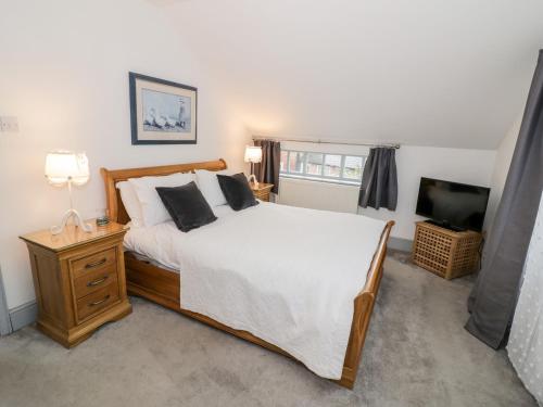 a bedroom with a large bed and a television at Homestead Cottage in Shipston on Stour