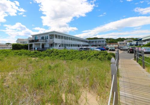 a building on a beach next to a wooden boardwalk at On the Beach Motel in Old Orchard Beach