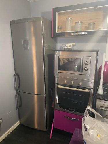eine Küche mit einem Kühlschrank aus Edelstahl und einer Mikrowelle in der Unterkunft Casa en la playa in Pobra do Caramiñal