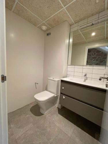 a bathroom with a toilet and a sink and a mirror at Casa Bayer in Benicàssim