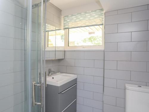 biała łazienka z umywalką i oknem w obiekcie Ty Melyn w mieście Rhosneigr