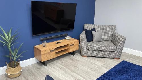 ein Wohnzimmer mit einem Stuhl und einem TV in der Unterkunft The Store, Luxury modern conversion with open plan living - Sleeps 4 in Wick