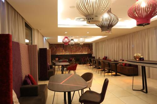 ein Restaurant mit Tischen, Stühlen und Kronleuchtern in der Unterkunft arte Hotel Linz in Linz