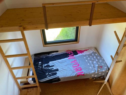 niewielka sypialnia z łóżkiem piętrowym i oknem w obiekcie tiny house du poulloguer w mieście Prat