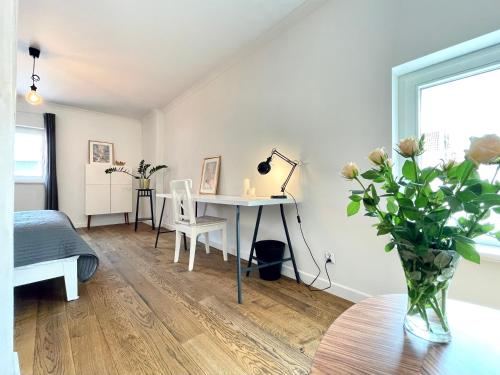 a bedroom with a desk and a table with a vase of flowers at Two-story Old Town Apartment in Toruń