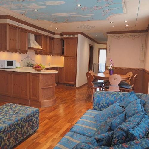 a living room with a blue couch and a kitchen at Il nido incantato in Andalo