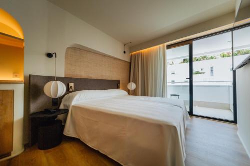 een slaapkamer met een groot bed en een groot raam bij El Hotel Pacha - Free Entrance to Pacha Club Included in Ibiza-stad