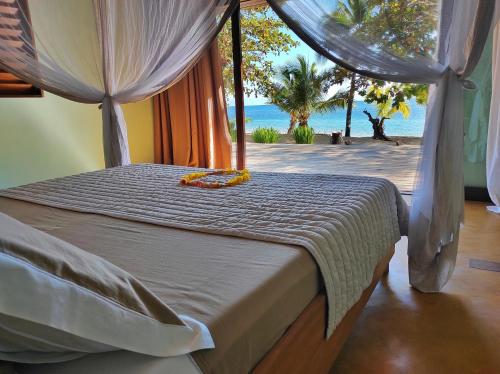 a bedroom with a bed with a view of the ocean at Eden Lodge in Madirokely