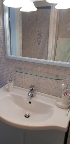a white bathroom sink with a mirror and toothbrushes at SUL MARE... in Misano Adriatico