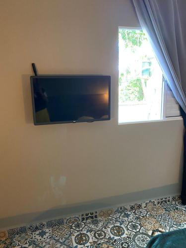 a flat screen tv on a wall next to a window at Santa Cecília Pousada in Guarujá