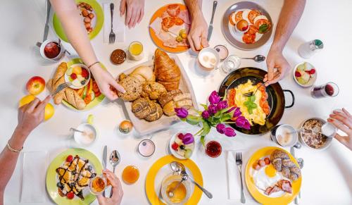 a group of people sitting around a table with breakfast foods at Ibis Styles Wien City in Vienna