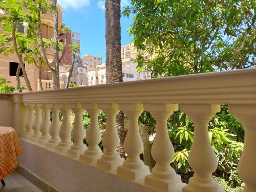 a white balcony with trees and buildings in the background at Vacation Apartments in a Private Villa with Private Beach Access in Alexandria