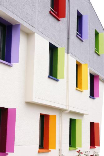 a building with many colorful windows on it at Kyriad Rennes Sud - Cesson Chantepie in Chantepie