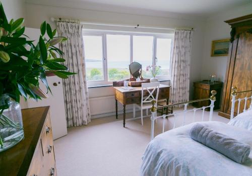 a bedroom with a desk and a bed and a window at Cae'r Borth in Moelfre