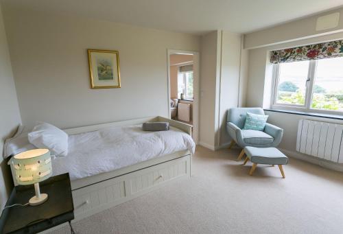 a bedroom with a bed and a chair and a window at Cae'r Borth in Moelfre