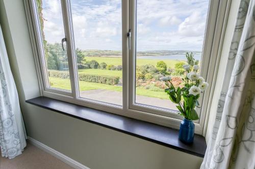 a window with a vase of flowers on a window sill at Cae'r Borth in Moelfre